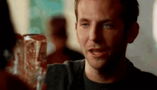 a man in a black shirt is sitting at a table with a can of soda in front of him .
