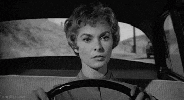 a woman is driving a car and looking out the window .