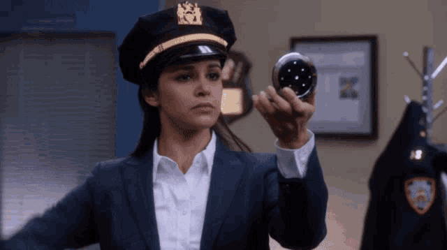 a woman wearing a police hat holds a mirror in her hand