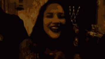 a blurry picture of a woman in a dark room with a man in the background .