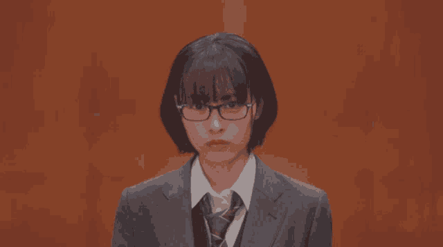 a girl wearing glasses and a suit looks serious