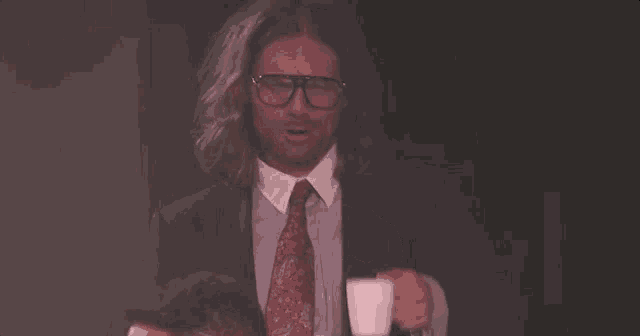 a man in a suit and tie is drinking a cup of coffee .