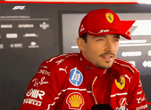 a man wearing a red hat with the number 16 on it is talking into a microphone