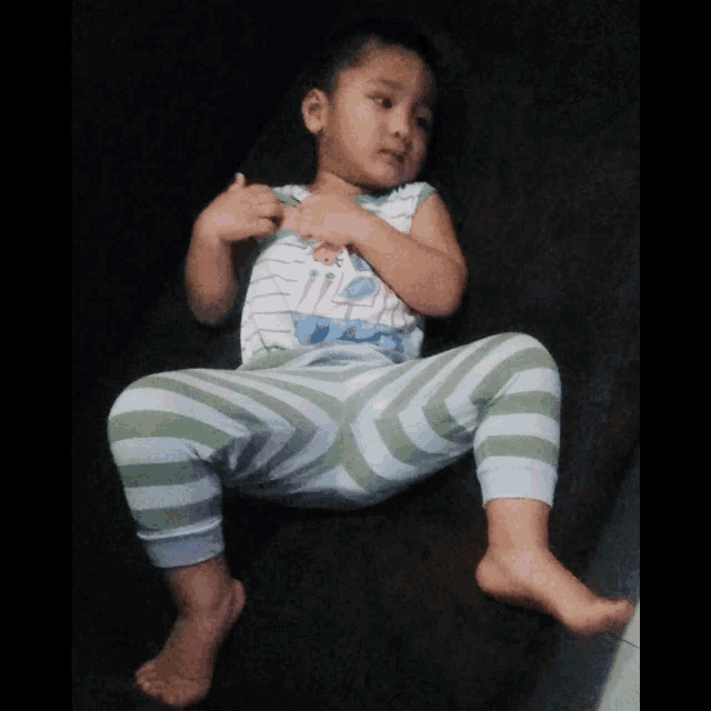 a little boy wearing striped pants and a shirt that says ' i love you '