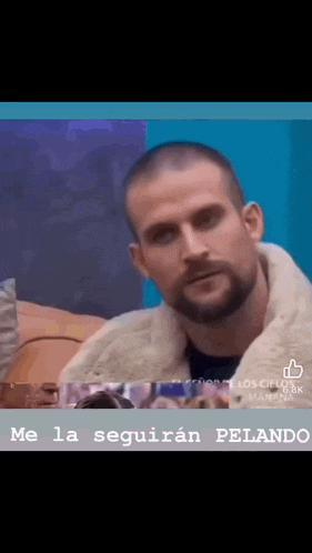 a man with a beard is sitting at a table with a sign that says " me la seguiran "
