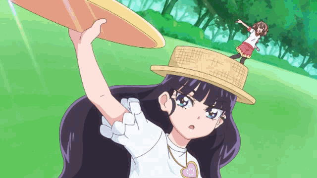 a girl in a straw hat is holding a frisbee over her head