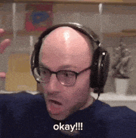 a bald man wearing headphones and glasses is saying okay !!!