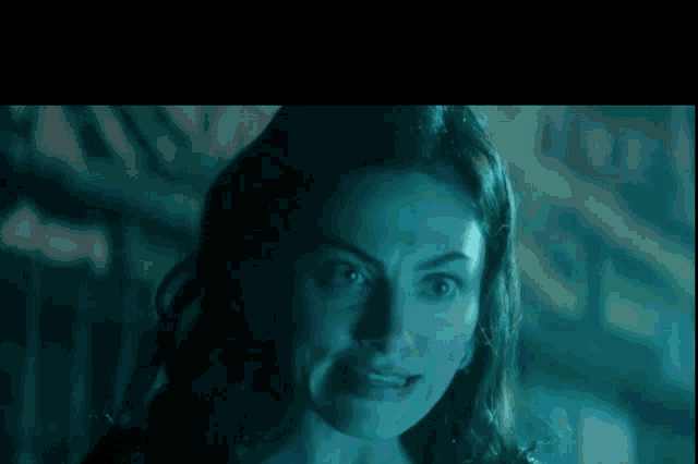 a close up of a woman 's face with a blue light behind her