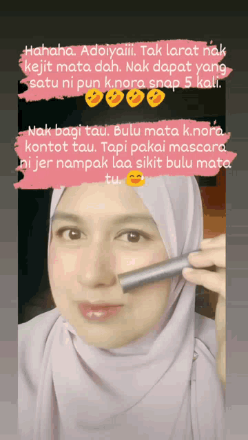 a woman wearing a hijab is holding a mascara tube