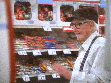 a man in a hat and suspenders is looking at candy on a shelf with a price tag that says 1.49