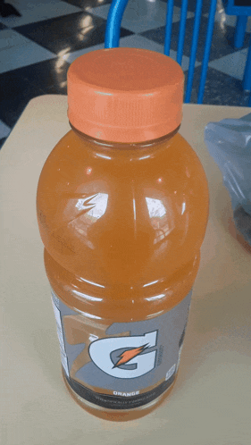 a bottle of orange gatorade is sitting on a table