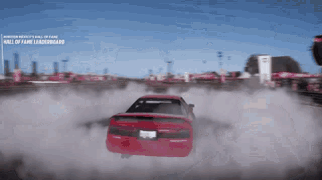 a red car is driving down a road with a sign that says hall of fame leaderboard on it