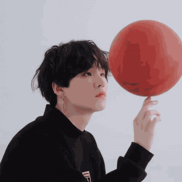 a young man holds a red basketball in his hand with the letter d on his shirt
