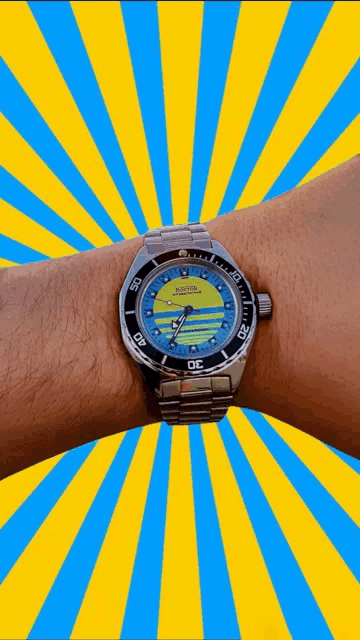 a person is wearing a watch with a yellow face and a blue band