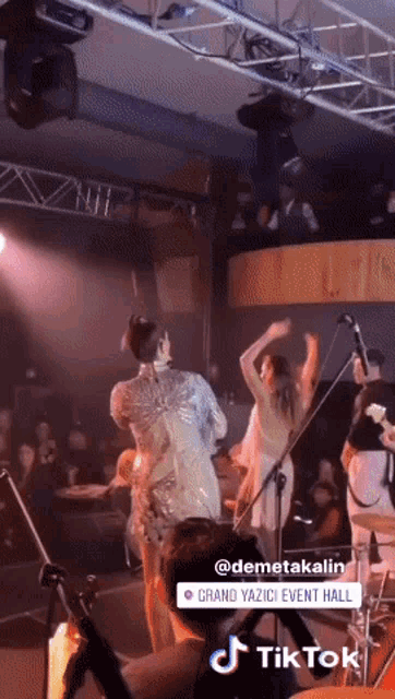 a group of people are dancing on a stage with a tiktok logo in the corner