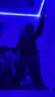 a person is dancing in a dark room with blue lights .