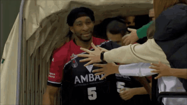 a man wearing a number 5 jersey is being hugged