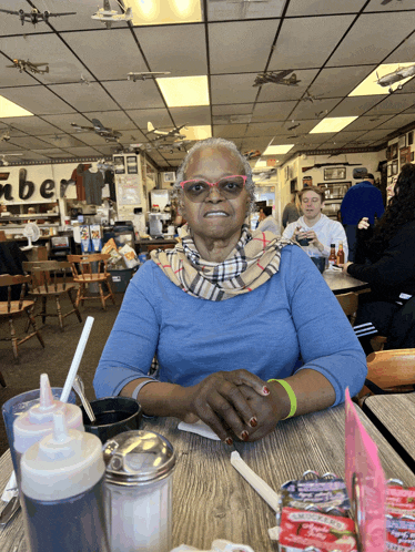 a woman sits at a table in a restaurant with a sign on the wall that says ' amber '