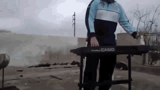 a man is playing a casio keyboard outside in the rain