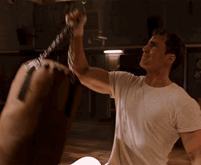 a man in a white t-shirt is holding a punching bag with a label that says ' a ' on it