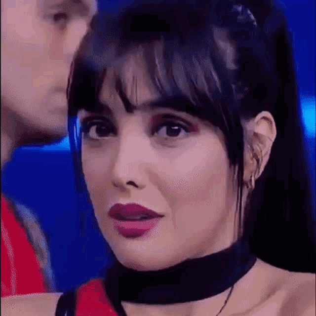 a close up of a woman wearing a choker and a red top .