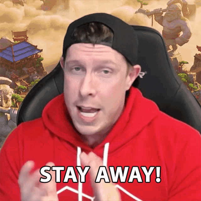 a man wearing a red hoodie and a black hat says stay away