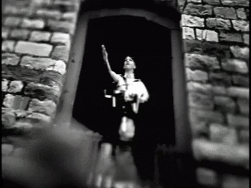 a black and white photo of a statue of liberty in front of a stone wall