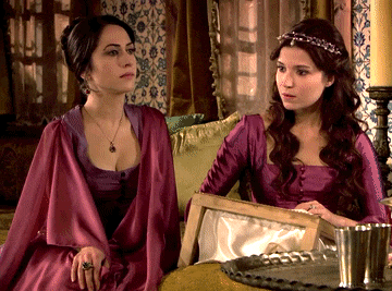 two women in purple dresses sit next to each other on a couch