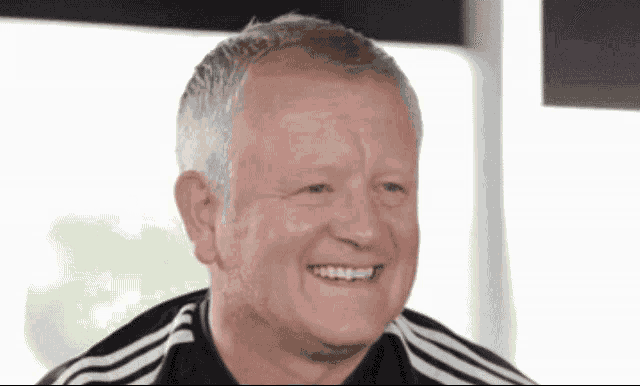 a man wearing a black and white adidas shirt smiles for the camera