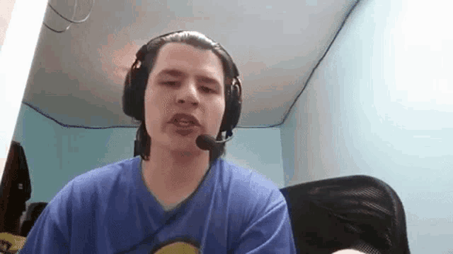a man wearing headphones and a microphone is sitting in front of a computer .