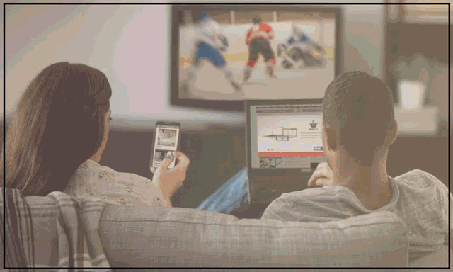 a man and a woman are watching a hockey game on a tv