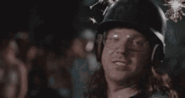 a man wearing a helmet and gloves is making a funny face with his mouth open .