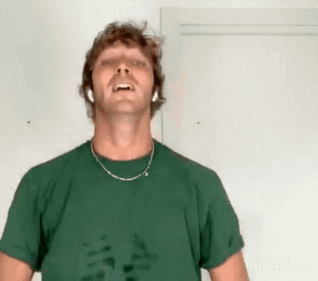 a man wearing a green t-shirt and headphones is giving a high five .