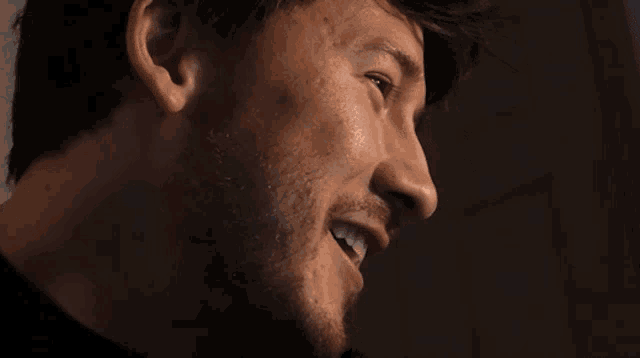 a close up of a man 's face with a beard in a dark room