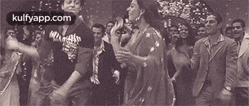 a group of people are dancing in a room with confetti falling from the ceiling .