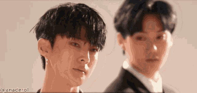 two young men in suits are standing next to each other and looking at the camera ..