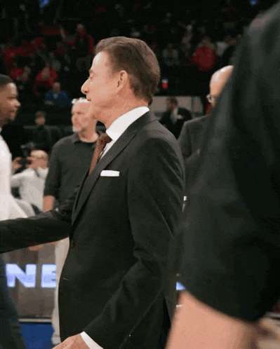 a man in a suit and tie shakes hands with another man in front of a sign that says ne
