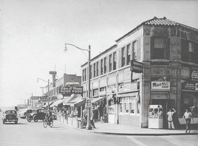 a black and white photo of a city street with a sign that says ' good food ' on it