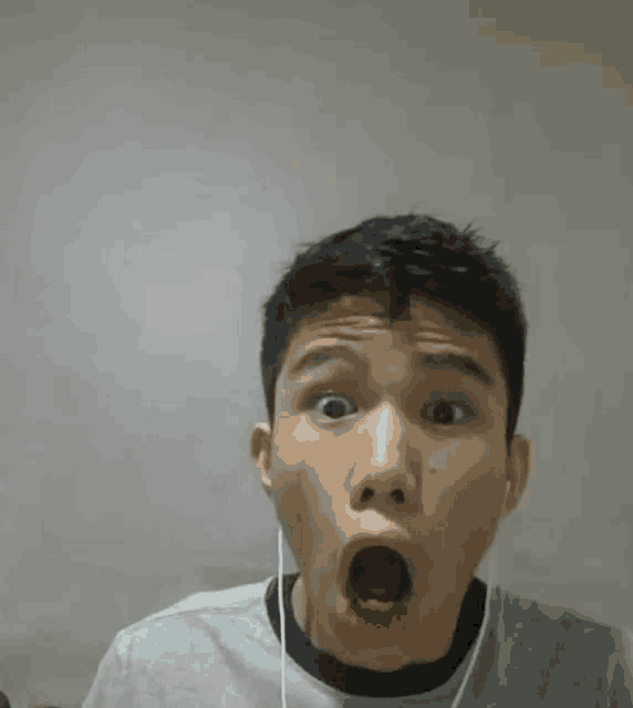 a young man wearing ear buds is making a funny face .