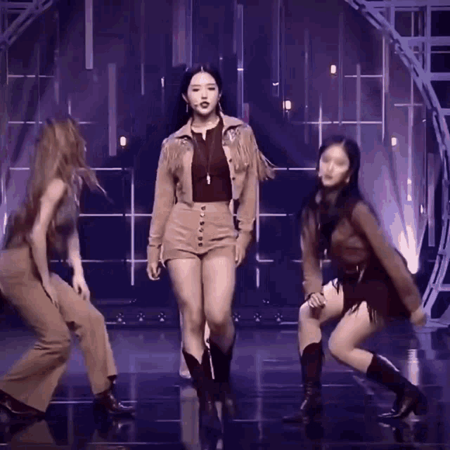 a woman in a fringed jacket and shorts is dancing with two other women
