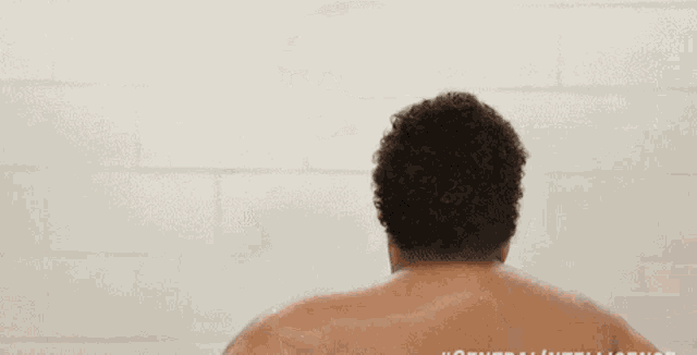 a shirtless man stands in front of a white wall with the words general intelligence written on the bottom