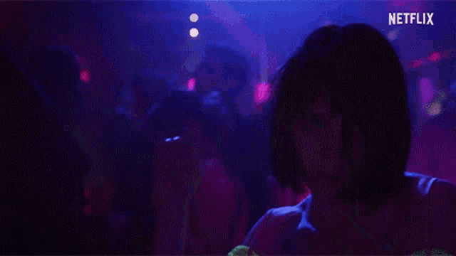 a woman is dancing in a dark room with netflix written on the bottom of the screen .