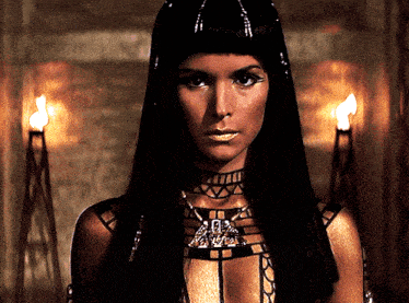 a woman with long black hair is wearing a necklace that says ' a ' on it