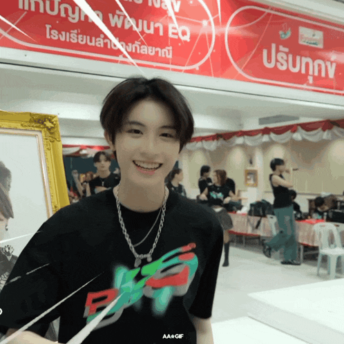 a man wearing a black shirt with the letter b on it smiles