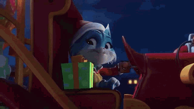 a cat in a santa hat is sitting in a sleigh holding a gift .