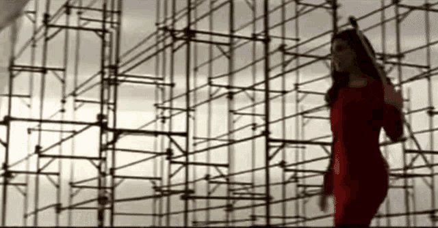 a woman in a red dress is standing in front of a scaffolding