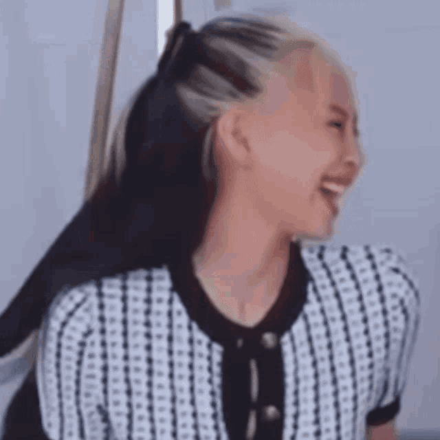 a woman with blonde hair is wearing a black and white striped shirt and smiling .