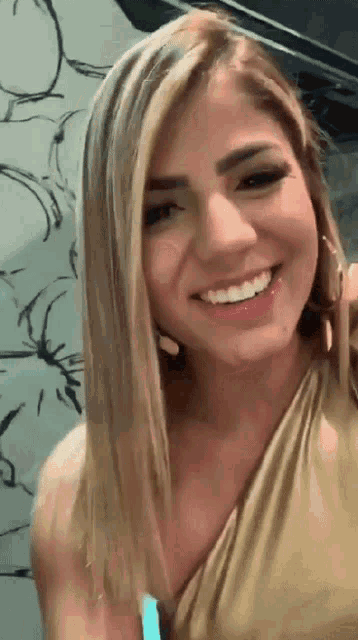 a woman in a gold dress is smiling for the camera
