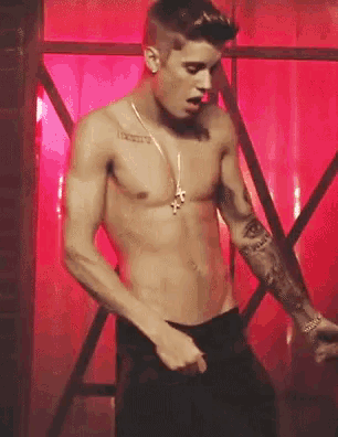 a shirtless man is standing in front of a red curtain .