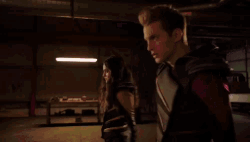 a man and a woman are standing next to each other in a dark room with purple lights coming out of them .